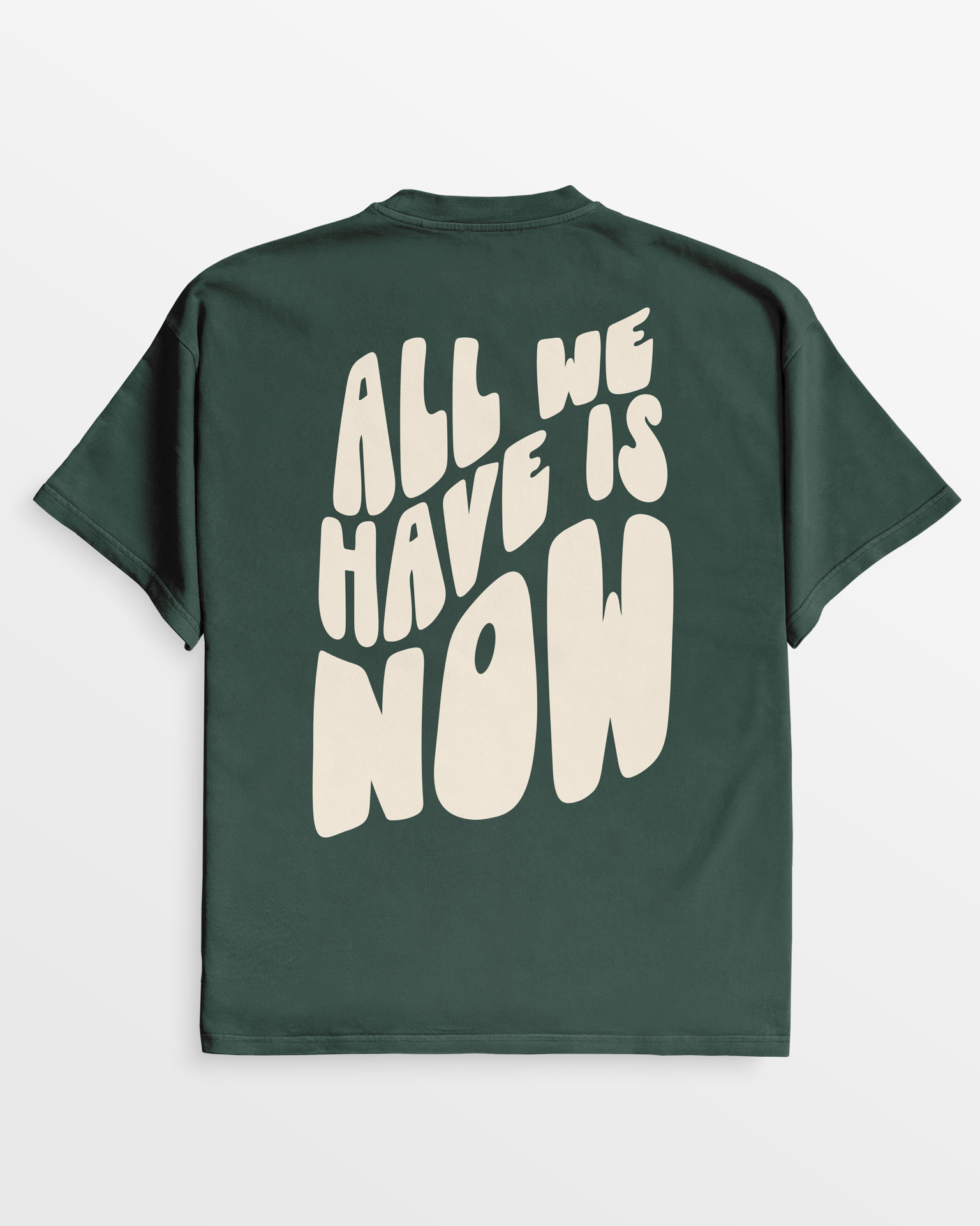 Rückseite des oversize 'All we have is now' T-Shirts in Wild-Grün mit großer cremefarbener Schrift, aus 100% Bio-Baumwolle.